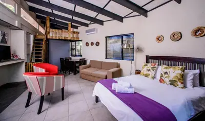 a bedroom with a bed and a living room at Zebrina Guest House in Nelspruit