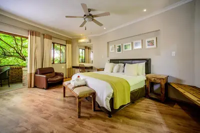 a bedroom with a large bed and a chair at Zebrina Guest House in Nelspruit