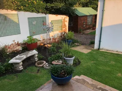 a garden with a bench and plants in a yard at Peace Corner Cottages in Dullstroom