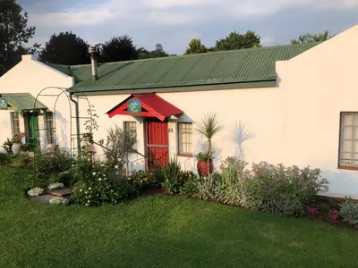 a house with a red door and a yard at Peace Corner Cottages in Dullstroom