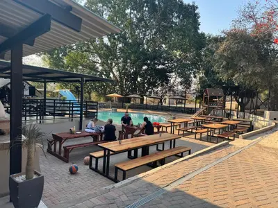 a group of people sitting at picnic tables by a pool at Mabalel in Crocodile Valley Estates