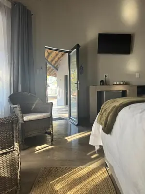 a bedroom with a bed and a chair and a television at Mabalel in Crocodile Valley Estates