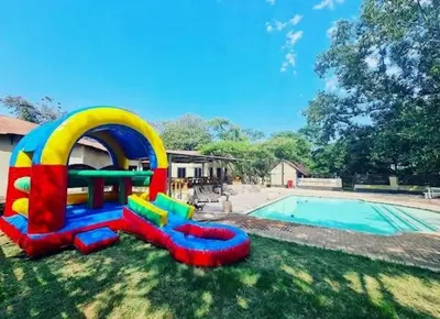 a playground in the grass next to a swimming pool at Mabalel in Crocodile Valley Estates