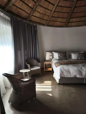 a bedroom with a bed and a chair at Mabalel in Crocodile Valley Estates