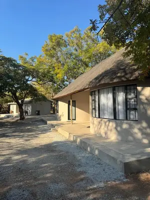a building with a thatched roof and a tree at Mabalel in Crocodile Valley Estates