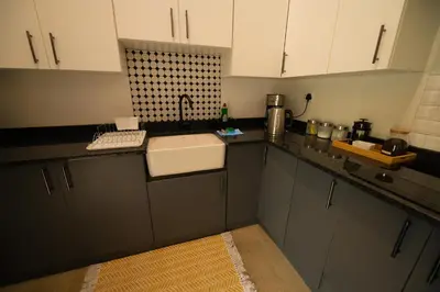 a kitchen with white cabinets and a sink at Oriole Bush Cottage in Hoedspruit