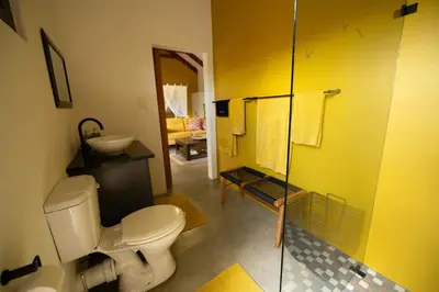 a bathroom with a toilet and a glass shower at Oriole Bush Cottage in Hoedspruit