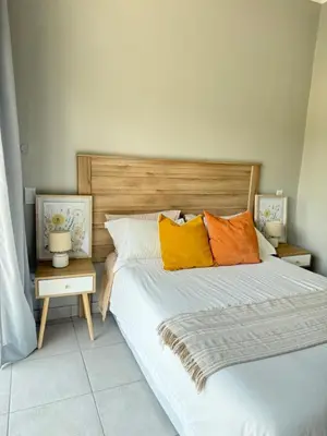 a bedroom with two beds with orange and yellow pillows at Thandekile Garden Venue in Midrand