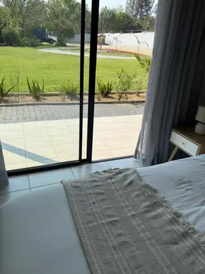 a bedroom with a bed and a view of a patio at Thandekile Garden Venue in Midrand