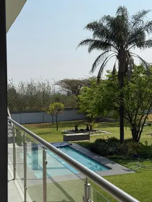 a balcony with a swimming pool and a palm tree at Thandekile Garden Venue in Midrand
