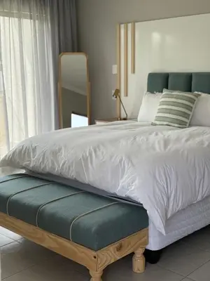 a bedroom with a bed with a green and white comforter at Thandekile Garden Venue in Midrand