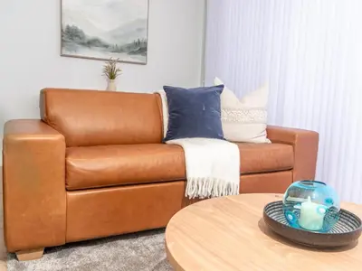 a brown leather couch in a living room with a table at Luxurious Apartment, Ellipse, Waterfall, Midrand in Midrand