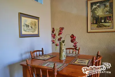a wooden table with two chairs and a vase on it at Sonata in Dullstroom