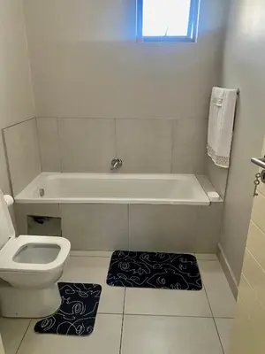a bathroom with a tub and a toilet and a rug at Ladybug unit 3 (2) in Midrand