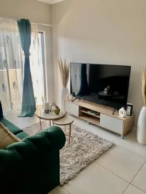 a living room with a large television and a green couch at Ladybug unit 3 (2) in Midrand