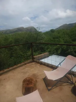 a balcony with a glass table and a chair at Hartbeest Bush Stay #4 in Hartbeespoort