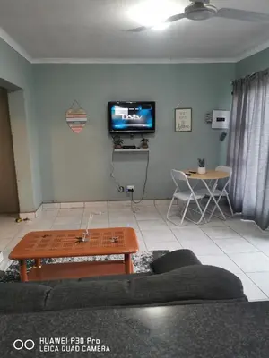 a living room with a couch and a table and a tv at A home away from Home in Musina