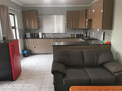 a living room with a couch in front of a kitchen at A home away from Home in Musina