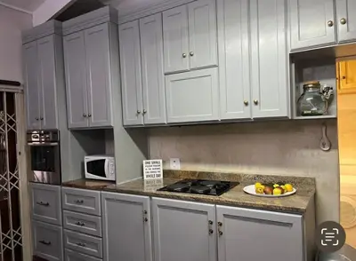 a kitchen with white cabinets and a bowl of fruit on the counter at Mi Casita in Graskop