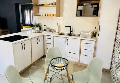 a kitchen with white cabinets and a table and chairs at Lemon Ivy Guesthouse in Polokwane