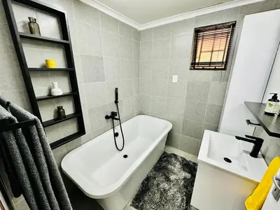 a bathroom with a white tub and a sink at Lemon Ivy Guesthouse in Polokwane