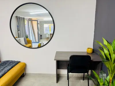 a mirror in a bedroom with a desk and a chair at Lemon Ivy Guesthouse in Polokwane