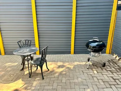 three chairs and a table and a grill on a patio at Lemon Ivy Guesthouse in Polokwane