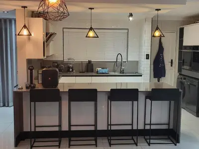 a kitchen with a counter with bar stools at DZUVHA BOUTIQUE VILLA in Hartbeespoort