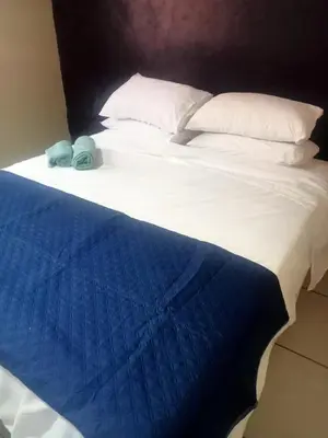 a bed with white sheets and a blue blanket at Queen Light in Pretoria