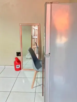 a chair sitting next to a refrigerator in a room at Queen Light in Pretoria