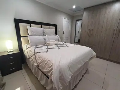 a bedroom with a large white bed with a wooden cabinet at Trumma Guest House in Pretoria