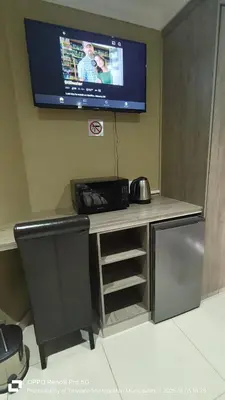 a tv on a wall with a desk with a television on it at Trumma Guest House in Pretoria