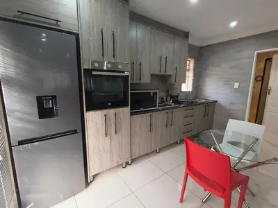a kitchen with a red chair and a refrigerator at Trumma Guest House in Pretoria