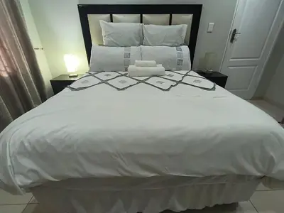 a large white bed with white sheets and pillows at Trumma Guest House in Pretoria