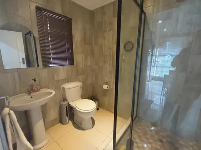 a bathroom with a toilet and a sink and a shower at Trumma Guest House in Pretoria