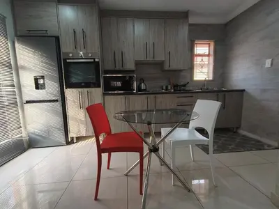 a kitchen with a glass table and two chairs at Trumma Guest House in Pretoria