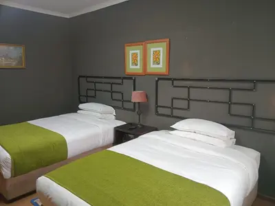 a bedroom with two beds with green and white sheets at Oteng Guest House in Belfast