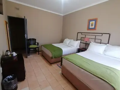 a hotel room with two beds and a chair at Oteng Guest House in Belfast