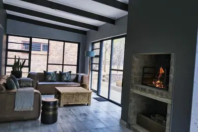 a living room with a couch and a fireplace at Woodpecker Villa Guesthouse in Thabazimbi