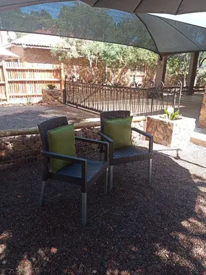 two chairs with green cushions sitting under an umbrella at Woodpecker Villa Guesthouse in Thabazimbi