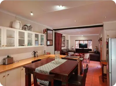 a kitchen and living room with a table and a dining room at Khalila's Equestrian Cottage in Midrand