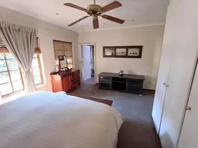 a bedroom with a bed and a ceiling fan at Khalila's Equestrian Cottage in Midrand