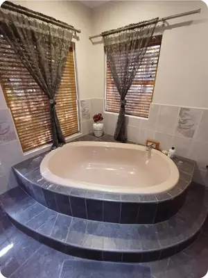 a large bath tub in a bathroom with windows at Khalila's Equestrian Cottage in Midrand