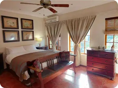 a bedroom with a large bed and a ceiling fan at Khalila's Equestrian Cottage in Midrand