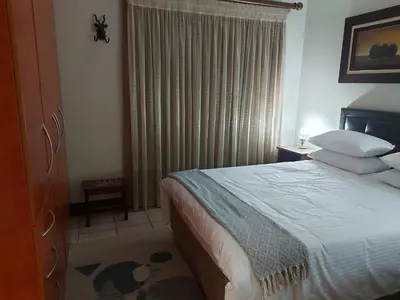 a bedroom with a bed and a window with curtains at Bella's Place in Pretoria