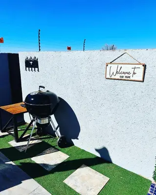 a grill in front of a white wall with a sign at The Pool_deck apartment in Lebowakgomo