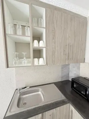 a kitchen with a sink and shelves with dishes at The Pool_deck apartment in Lebowakgomo
