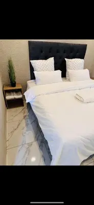 two beds with white sheets and a table with a plant at The Pool_deck apartment in Lebowakgomo