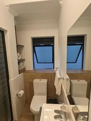 a bathroom with a toilet and a sink and two windows at Spacious 2 Bedroom Apartment in Midrand, Waterfall City - Business and Family friendly - 1 Elizabeth Place in Midrand