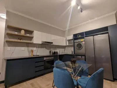 a kitchen with a glass table and blue chairs at Spacious 2 Bedroom Apartment in Midrand, Waterfall City - Business and Family friendly - 1 Elizabeth Place in Midrand